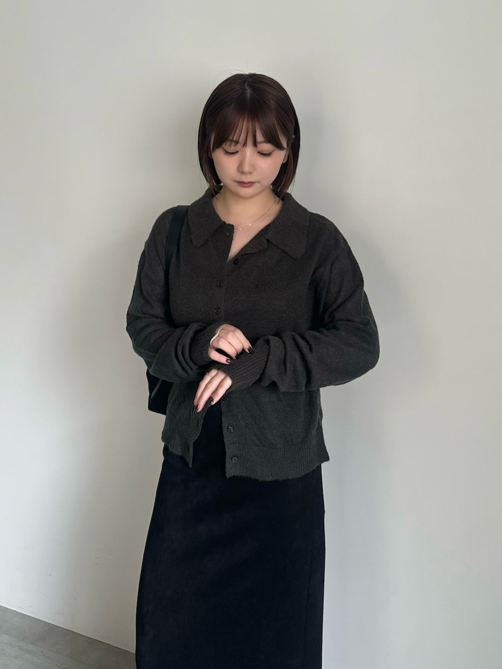 グレー系のカーディガン/ボレロ、ブラック系のスカート、ブラック系のローファーを着用したレディースの秋コーディネートの2枚目の写真