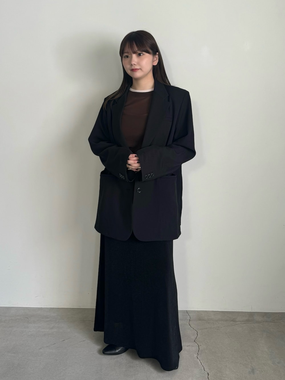 ブラウン系のTシャツ/カットソー、ブラック系のテーラードジャケット、ブラック系のスカートを着用したレディースの冬コーディネートの2枚目の写真