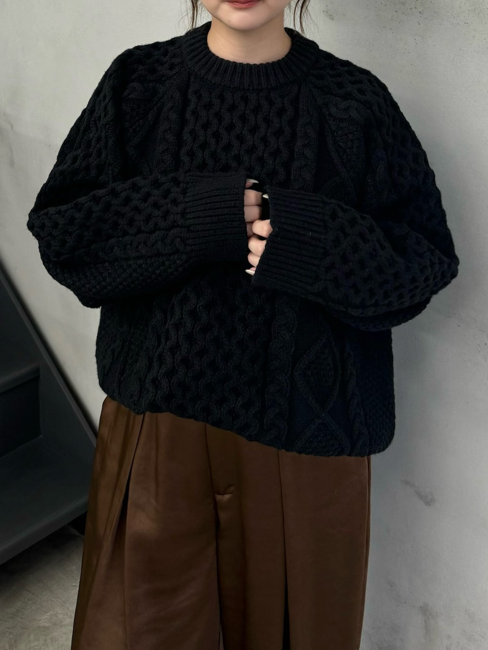 ブラック系のニット/セーター、ブラウン系のスラックス、ブラック系のブーツを着用したレディースの秋コーディネートの3枚目の写真