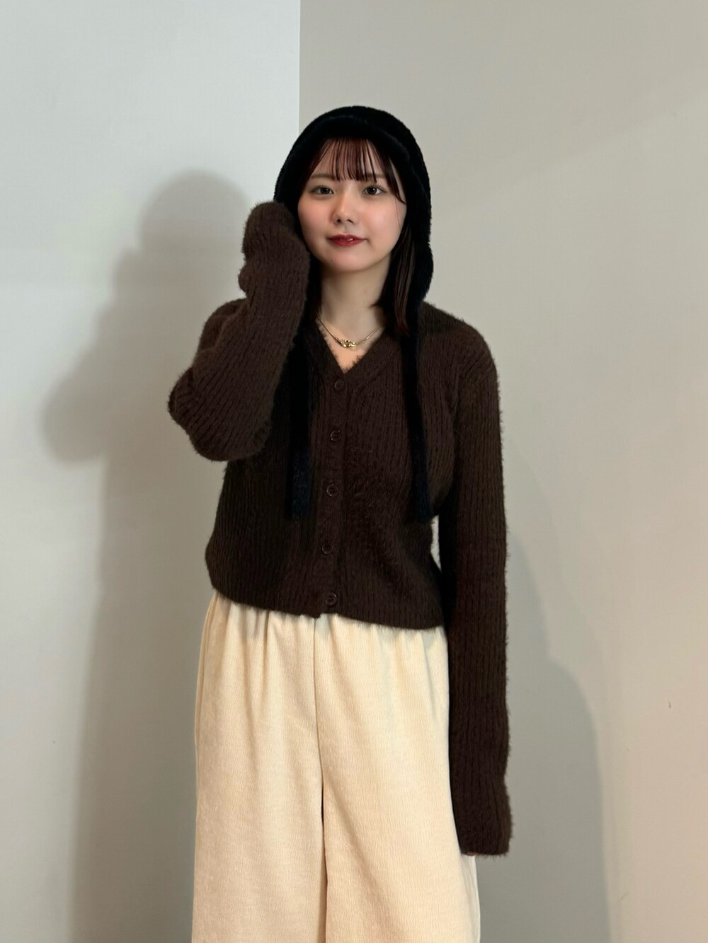 ブラウン系のカーディガン/ボレロ、ホワイト系のその他パンツ、ブラック系のブーツを着用したレディースの冬コーディネートの4枚目の写真