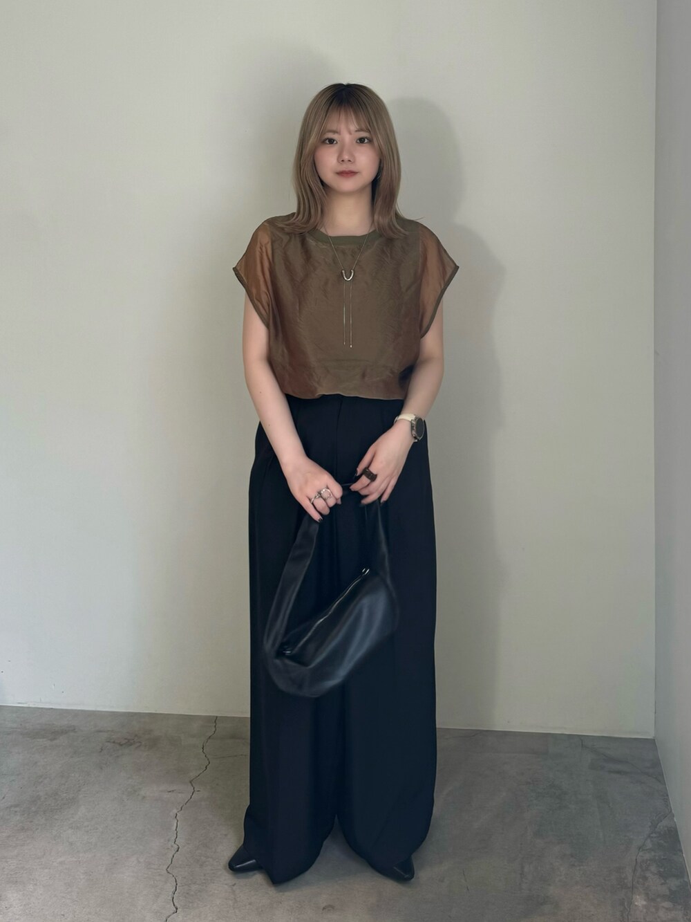 ブラック系のスラックス、ブラック系のサンダル、グリーン系のTシャツ/カットソーを着用したレディースの春コーディネートの2枚目の写真
