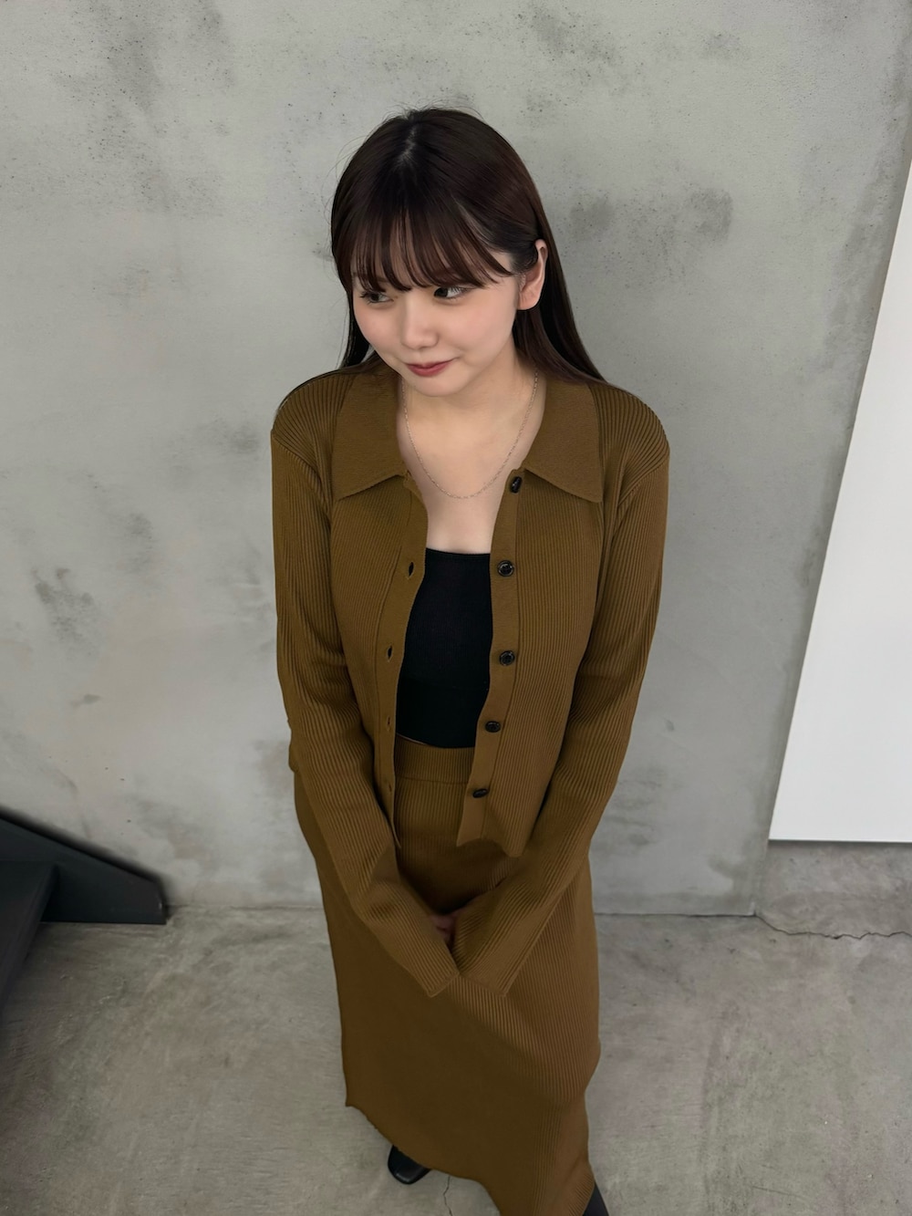 イエロー系のスカート、イエロー系のカーディガン/ボレロ、ブラック系のキャミソールを着用したレディースの冬コーディネートの3枚目の写真