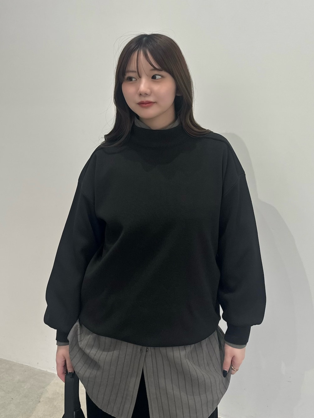 ブラック系のニット/セーター、グレー系のシャツ/ブラウス、ブラック系のスカートを着用したレディースの冬コーディネートの2枚目の写真