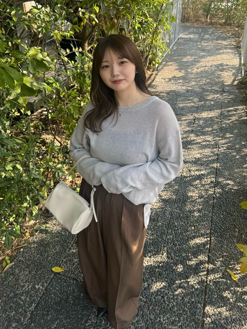 ブラック系のキャミソール、グレー系のニット/セーター、ブラウン系のスラックスを着用したレディースの春コーディネートの6枚目の写真