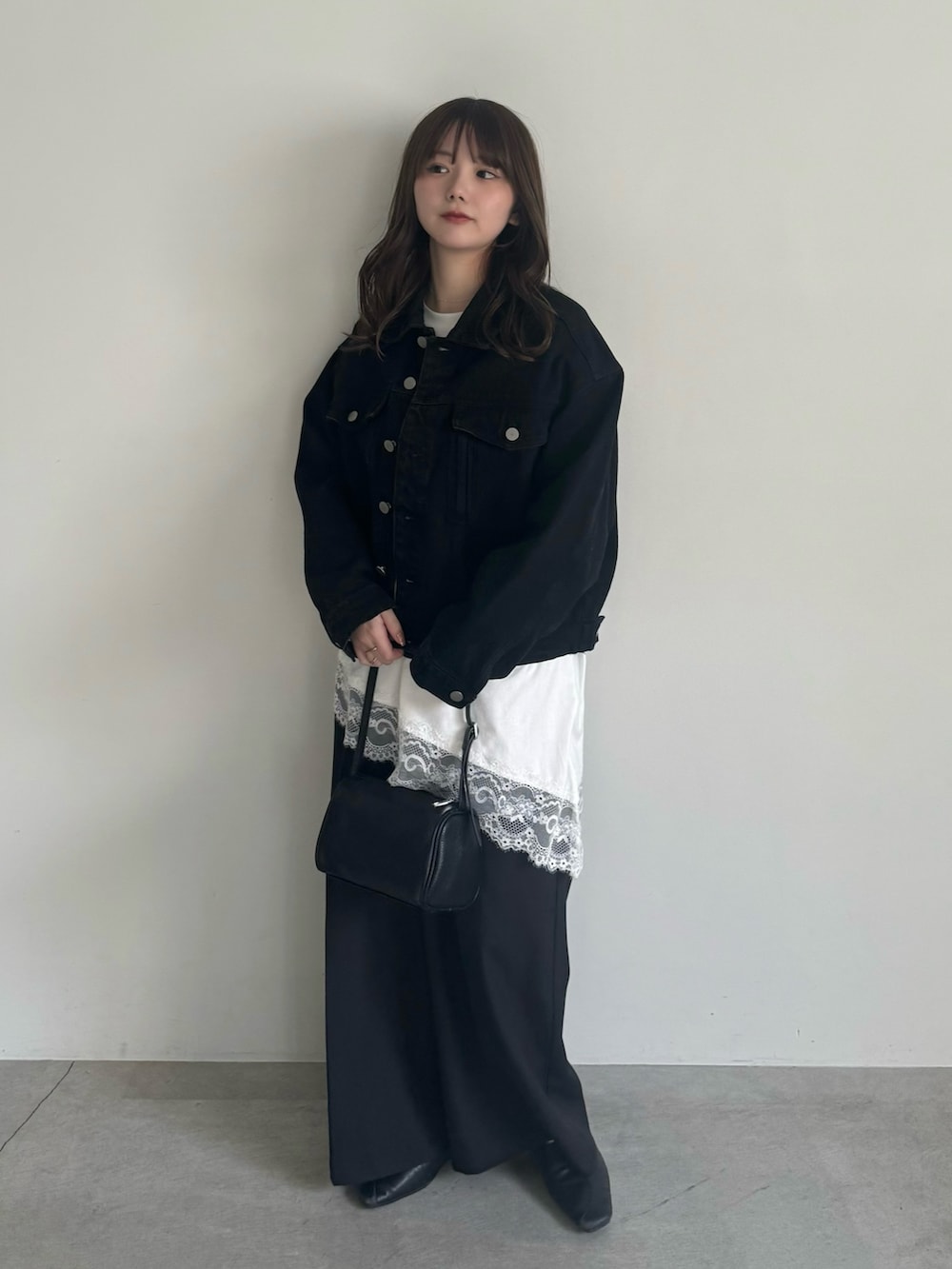 ブラック系のデニムジャケット、ブラック系のスラックスを着用したレディースの冬コーディネートの2枚目の写真