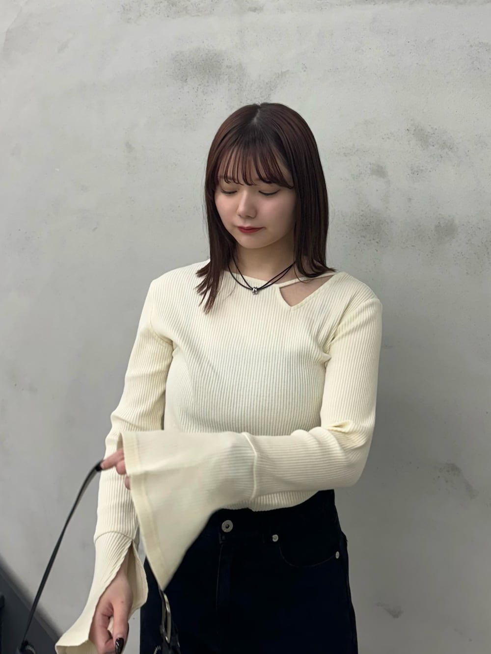 ブラック系のデニムパンツ、ブラック系のショルダーバッグ、ホワイト系のTシャツ/カットソーを着用したレディースの冬コーディネートの4枚目の写真