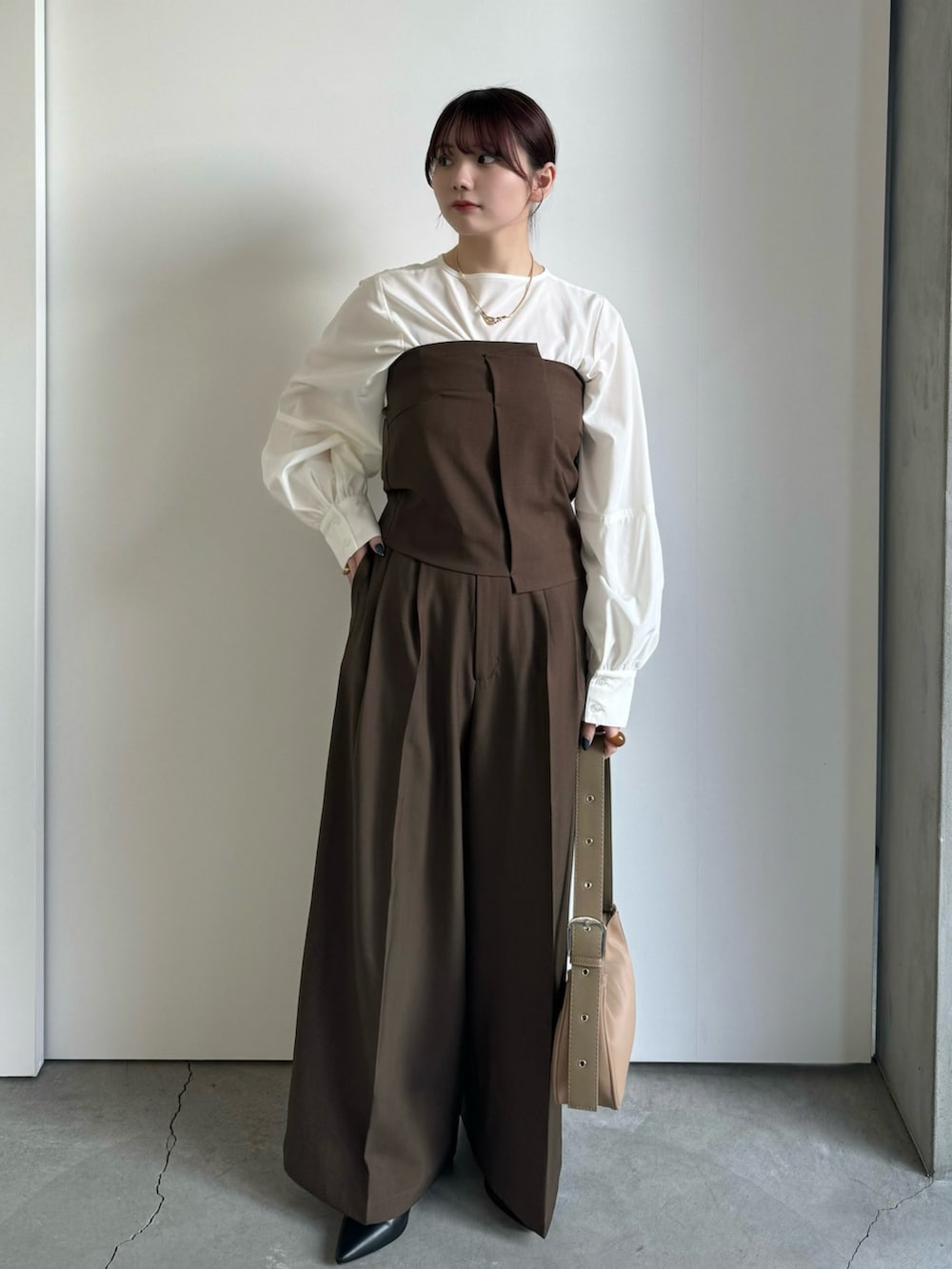 ブラウン系のスラックス、ホワイト系のシャツ/ブラウス、ブラウン系のチューブトップを着用したレディースの冬コーディネートの3枚目の写真