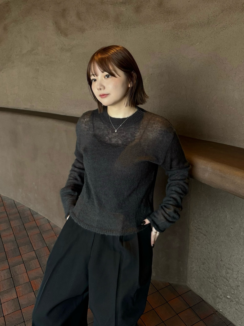 グレー系のニット/セーター、ブラック系のキャミソール、ブラック系のスラックスを着用したレディースの秋コーディネートの4枚目の写真