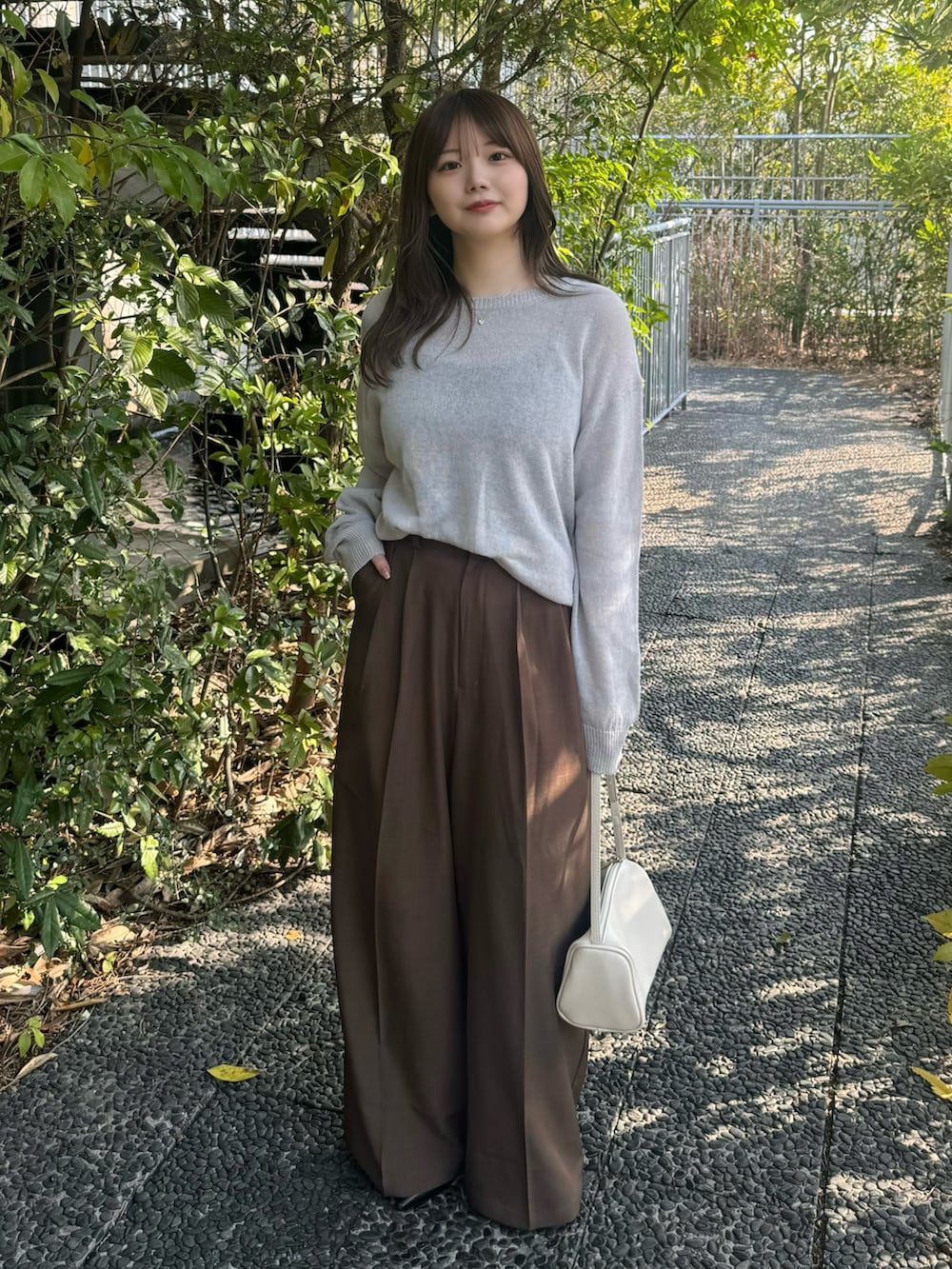 ブラック系のキャミソール、グレー系のニット/セーター、ブラウン系のスラックスを着用したレディースの春コーディネートの3枚目の写真