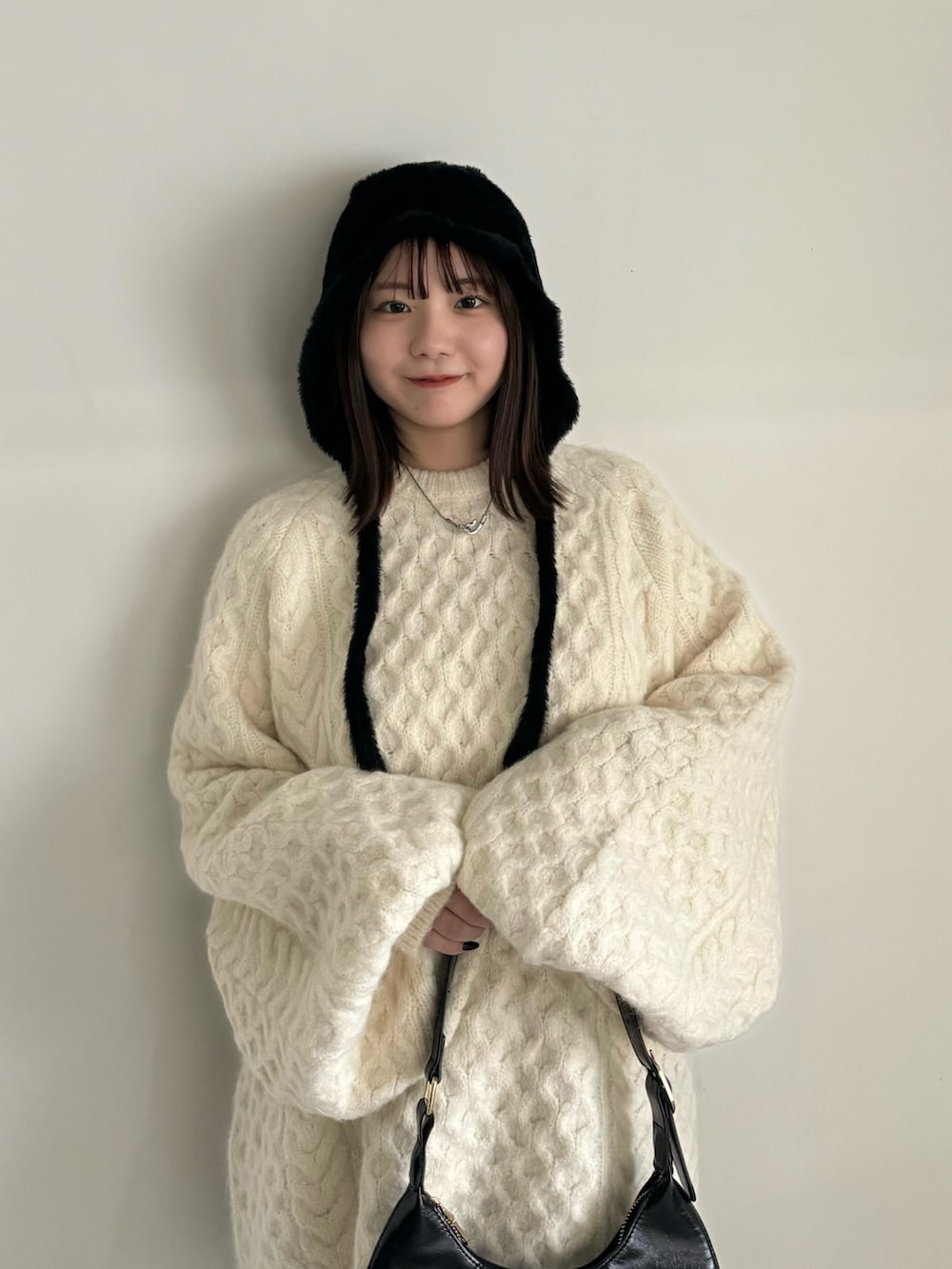 ホワイト系のニット/セーター、グレー系のその他パンツ、ブラック系のハンドバッグを着用したレディースの秋コーディネートの4枚目の写真