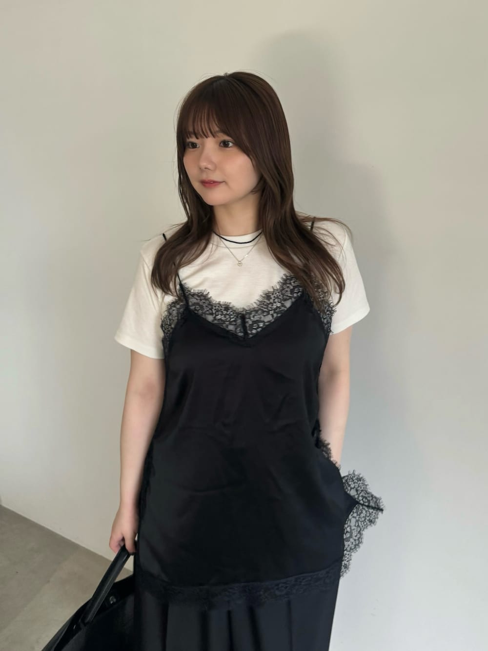 ブラック系のキャミソール、ブラック系のスラックス、ブラック系のハンドバッグを着用したレディースの春コーディネートの7枚目の写真