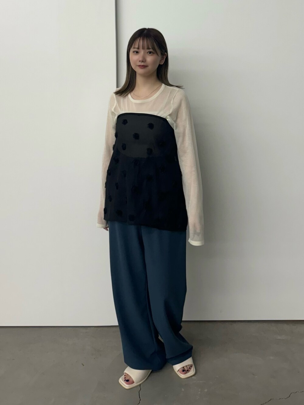 ブラック系のスカート、ホワイト系のニット/セーター、ホワイト系のキャミソールを着用したレディースの夏コーディネートの3枚目の写真