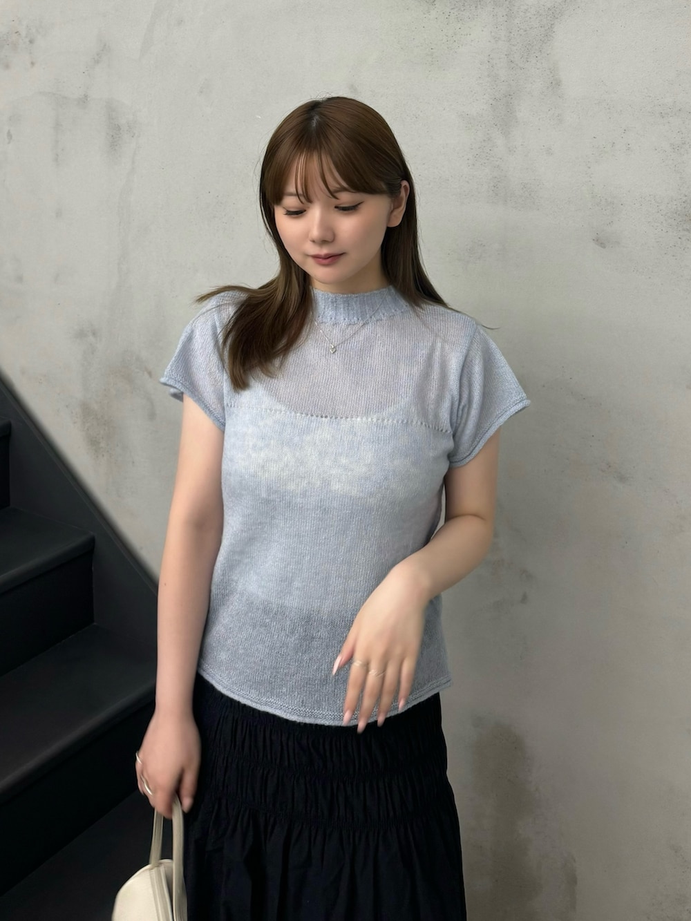 ブルー系のニット/セーター、ホワイト系のキャミソール、ブラック系のスカートを着用したレディースの夏コーディネートの4枚目の写真