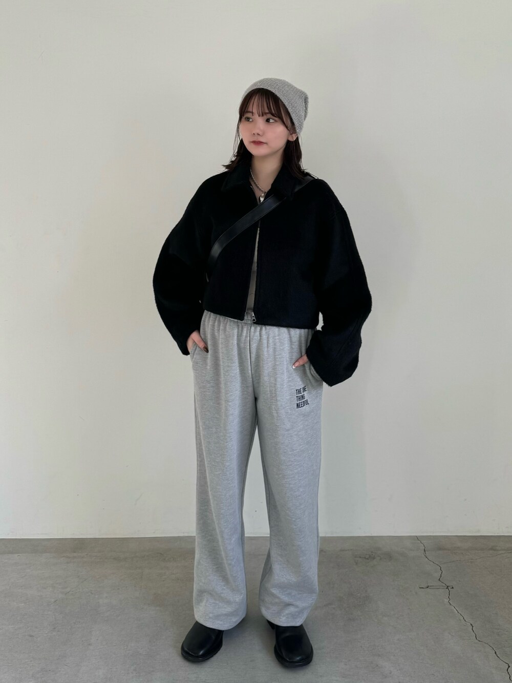 グレー系のスウェットパンツ、ブラック系のショルダーバッグ、ブラック系のステンカラーコートを着用したレディースの秋コーディネートの2枚目の写真