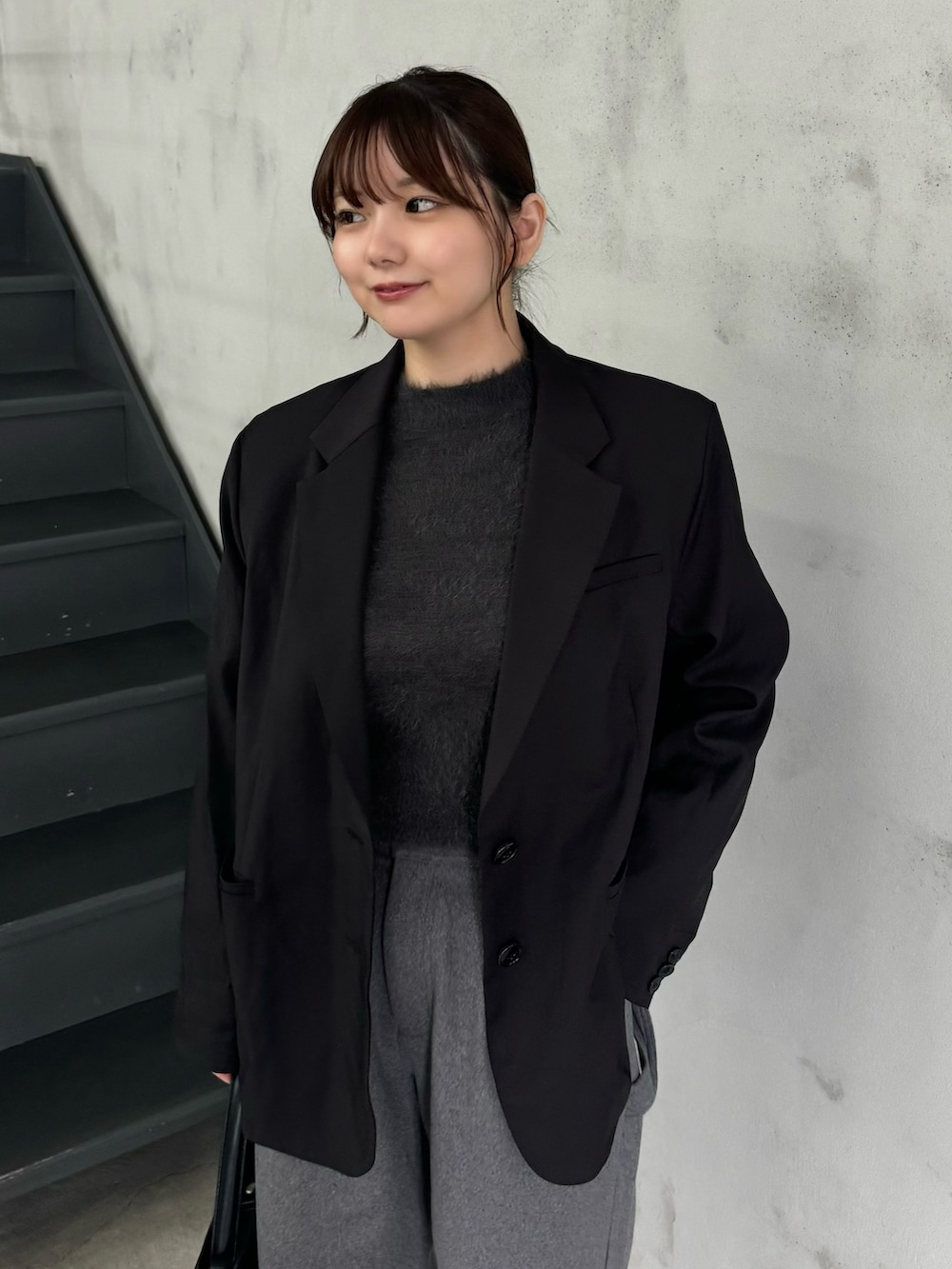 グレー系のニット/セーター、ブラック系のテーラードジャケット、グレー系のスラックスを着用したレディースの冬コーディネートの4枚目の写真