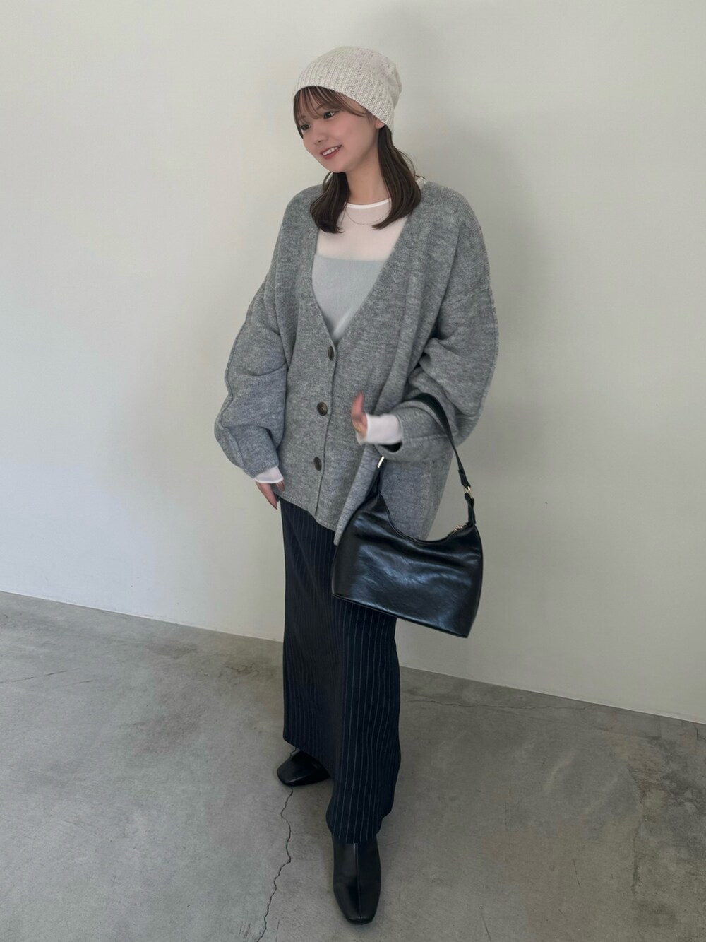 ベージュ系のカーディガン/ボレロ、ホワイト系のTシャツ/カットソー、ブルー系のスカートを着用したレディースの秋コーディネートの3枚目の写真