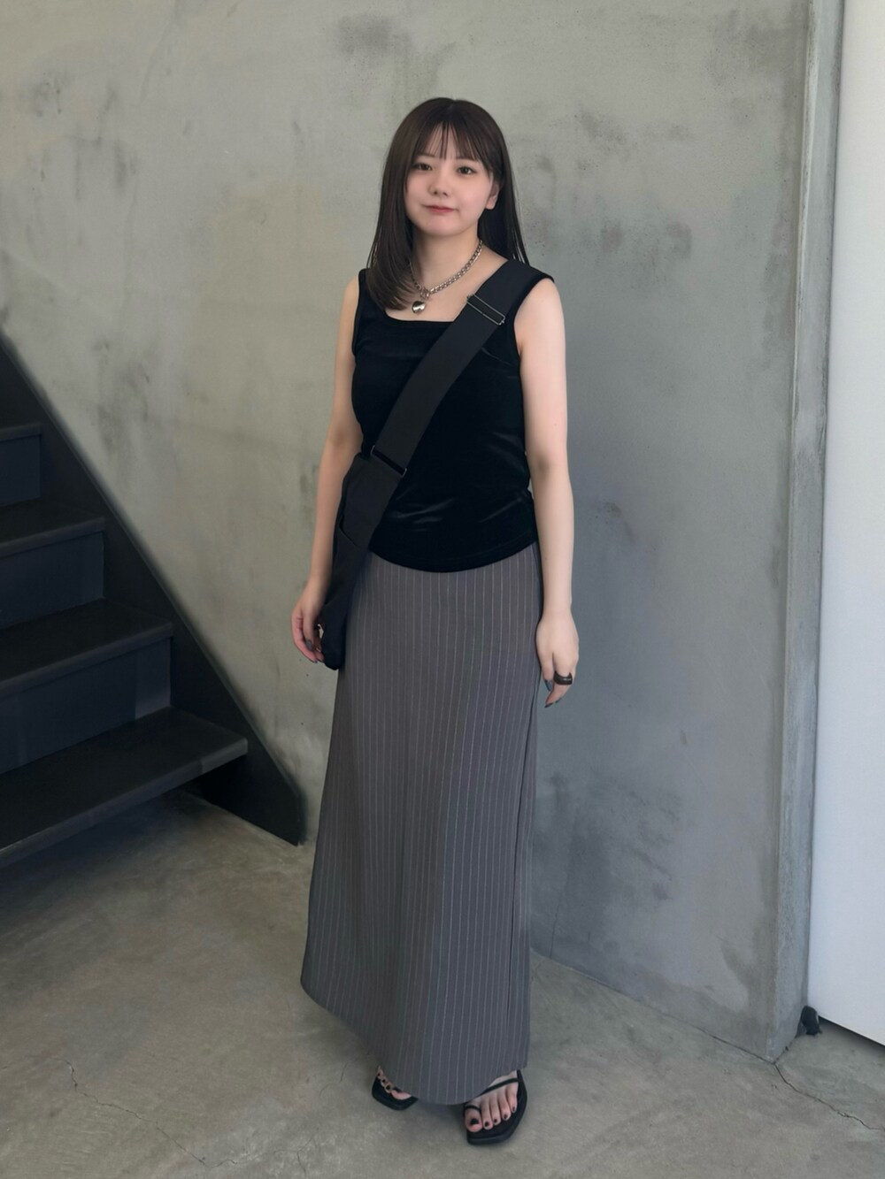 グレー系のスカート、ブラック系のショルダーバッグ、ブラック系のタンクトップを着用したレディースの夏コーディネートの4枚目の写真
