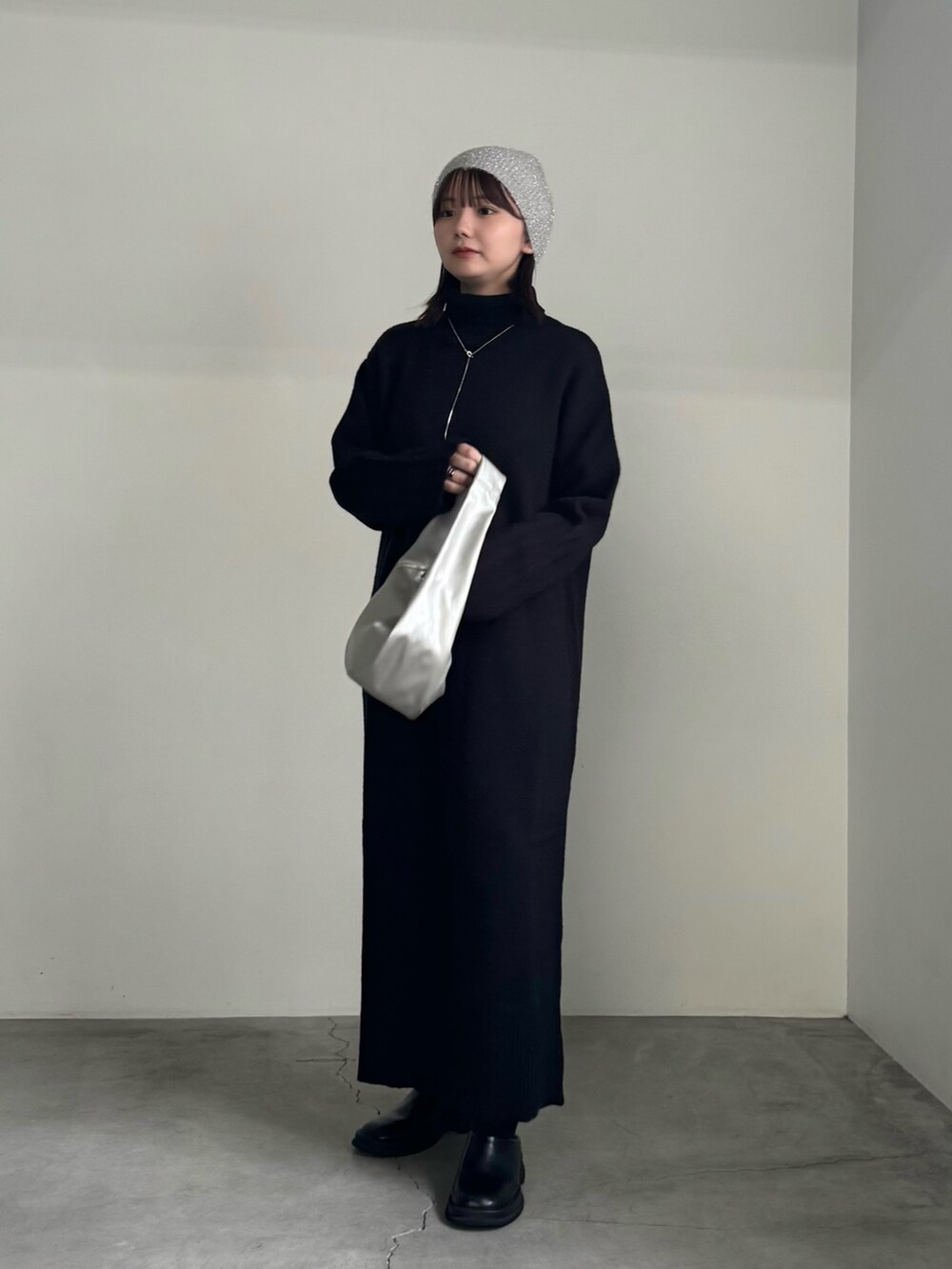 ブラック系のワンピース、シルバー系のショルダーバッグ、ブラック系のブーツを着用したレディースの秋コーディネートの2枚目の写真