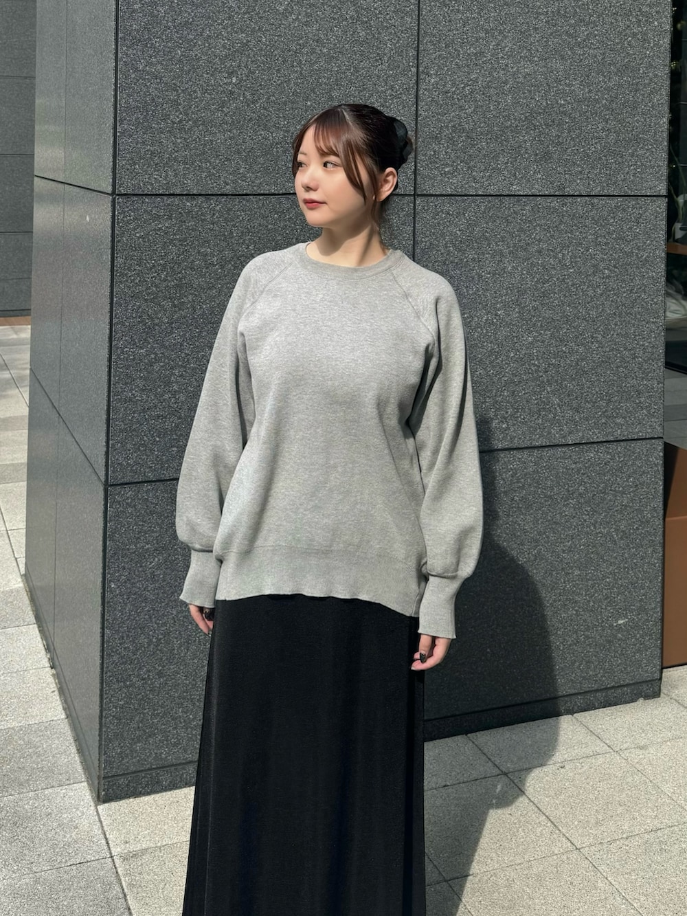 グレー系のニット/セーター、ブラック系のスカートを着用したレディースの秋コーディネートの3枚目の写真