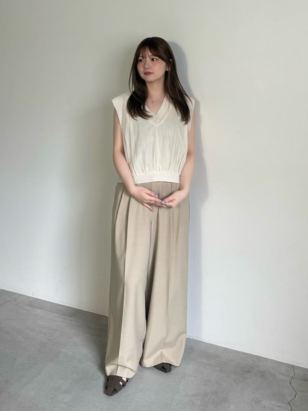 ベージュ系のベスト、ブラック系のキャミソール、ベージュ系のスラックスを着用したレディースの夏コーディネートの3枚目の写真