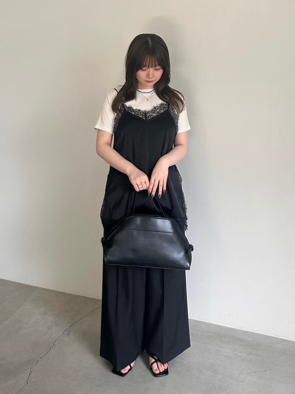 ブラック系のキャミソール、ブラック系のスラックス、ブラック系のハンドバッグを着用したレディースの春コーディネートの2枚目の写真