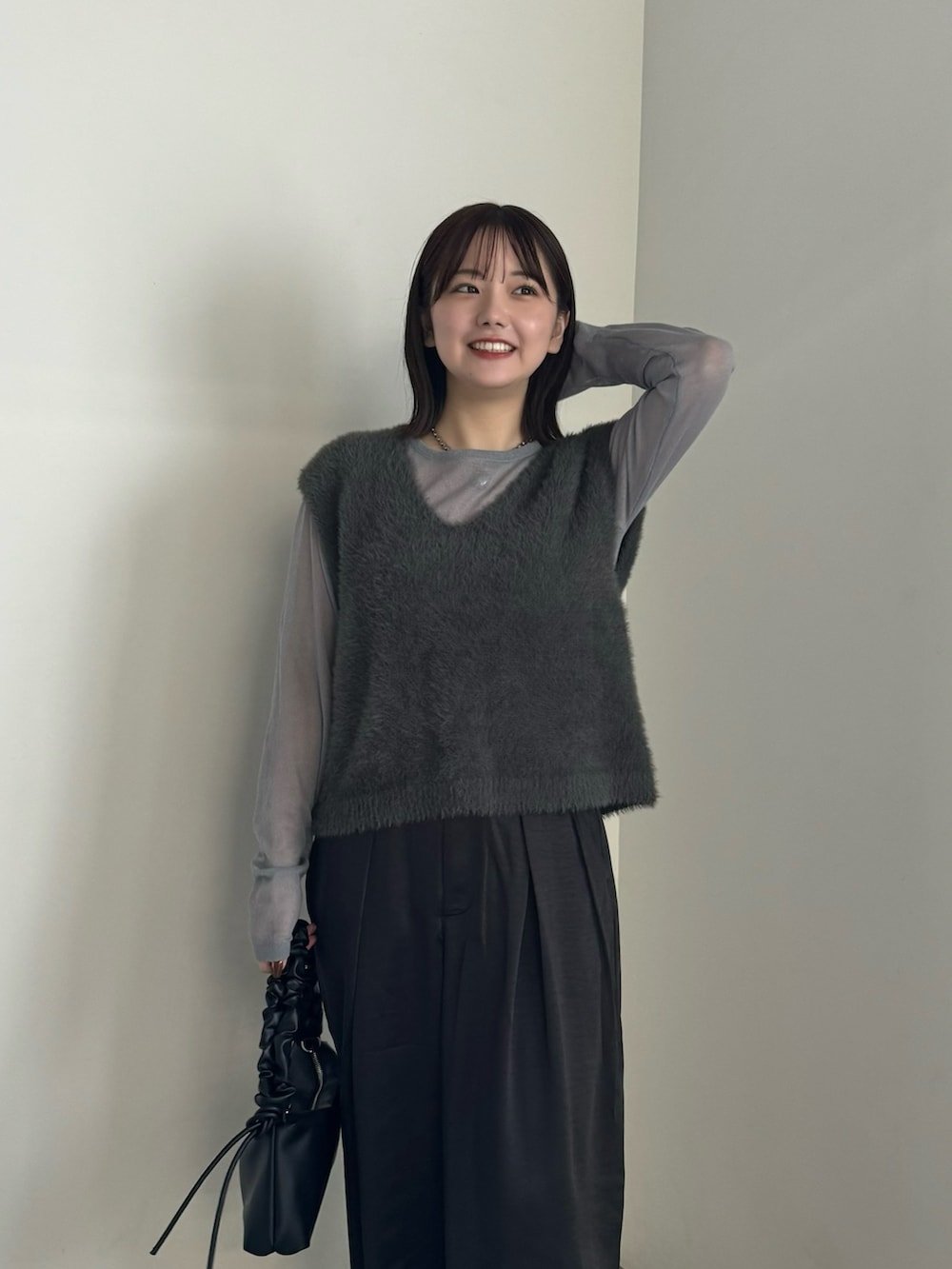 グレー系のベスト、グレー系のニット/セーター、ブラック系のスラックスを着用したレディースの秋コーディネートの4枚目の写真