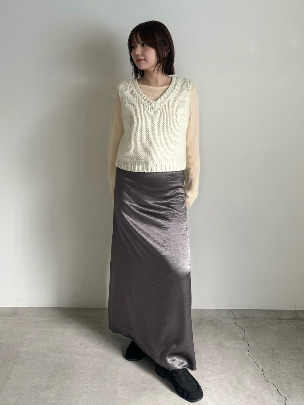 ホワイト系のベスト、ベージュ系のTシャツ/カットソー、グレー系のスカートを着用したレディースの秋コーディネートの2枚目の写真
