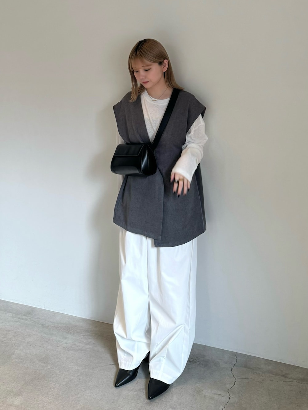 グレー系のベスト、ホワイト系のTシャツ/カットソー、ブラック系のキャミソールを着用したレディースの春コーディネートの3枚目の写真