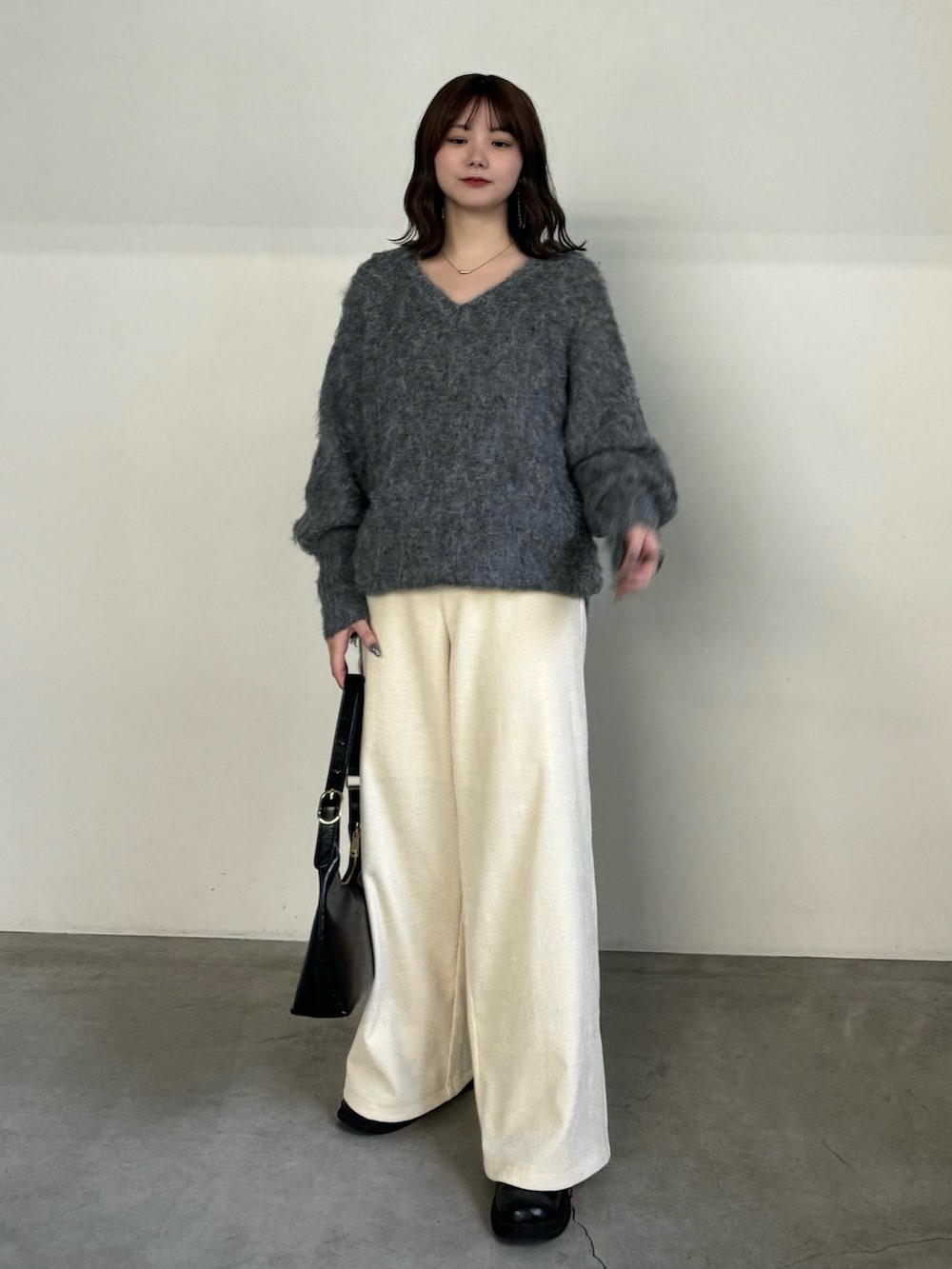 グレー系のニット/セーター、ホワイト系のその他パンツ、ブラック系のハンドバッグを着用したレディースの冬コーディネートの3枚目の写真
