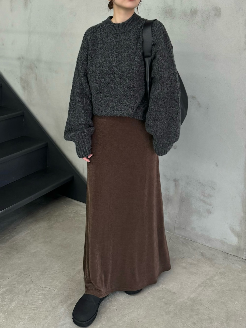グレー系のニット/セーター、ブラウン系のスカート、ブラック系のスリッポンを着用したレディースの冬コーディネートの3枚目の写真