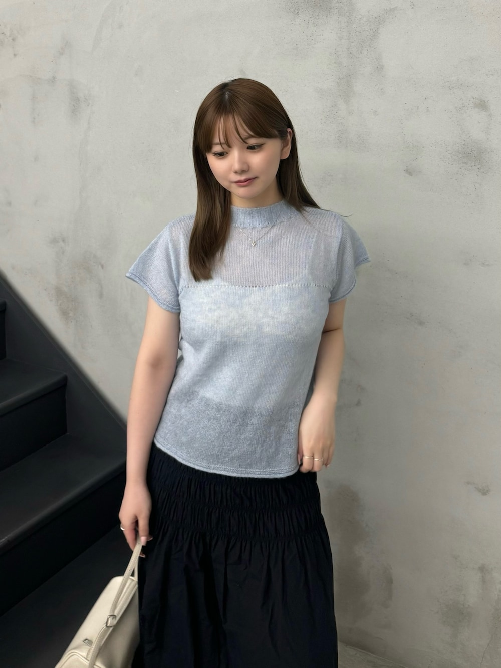 ブルー系のニット/セーター、ホワイト系のキャミソール、ブラック系のスカートを着用したレディースの夏コーディネートの5枚目の写真