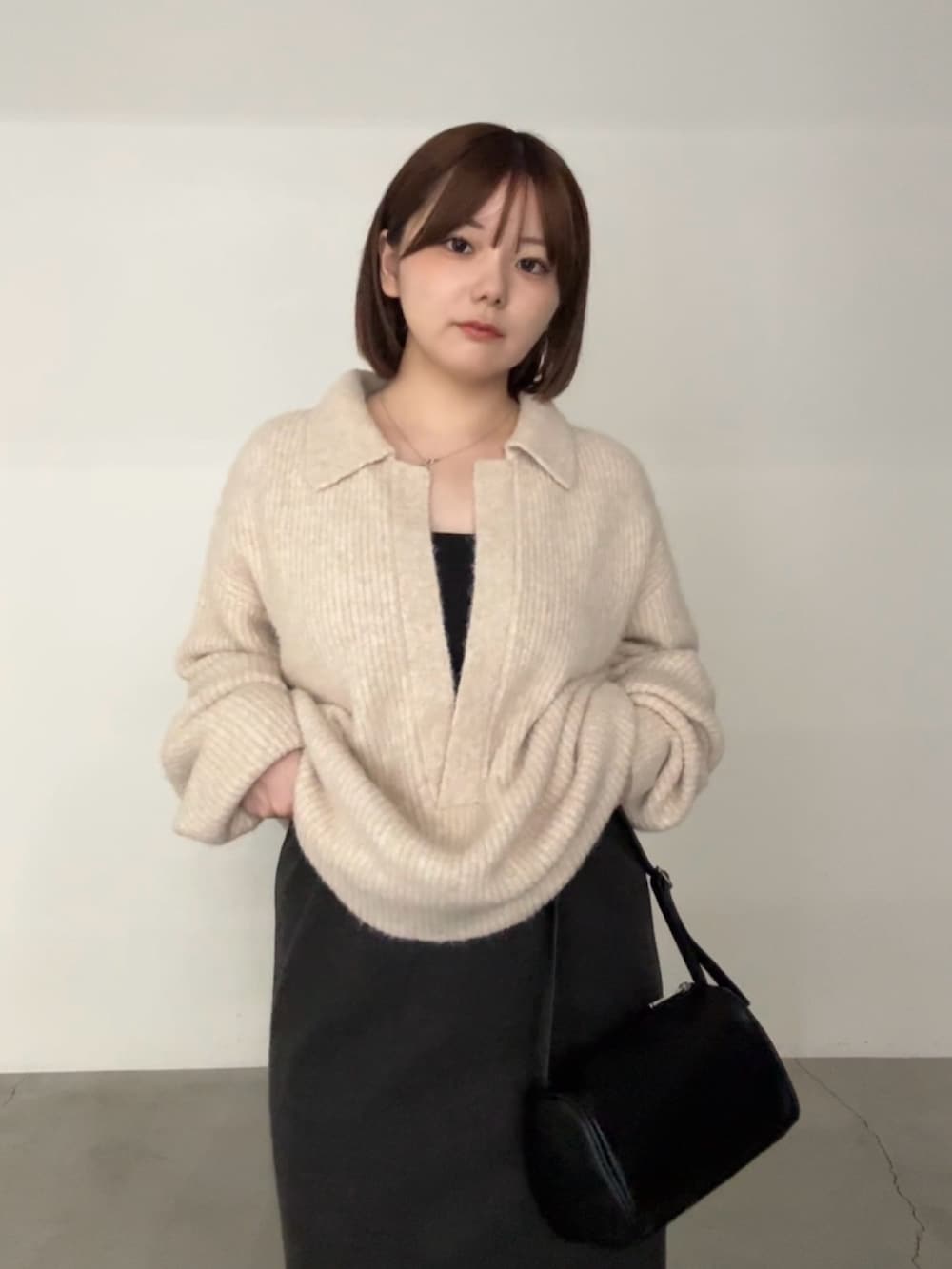 ベージュ系のニット/セーター、ブラック系のキャミソール、グレー系のスカートを着用したレディースの秋コーディネートの3枚目の写真