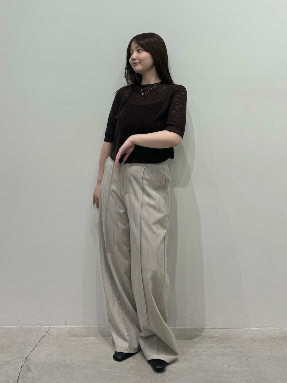 ブラウン系のニット/セーター、グレー系のスラックス、ブラック系のスリッポンを着用したレディースの春コーディネートの2枚目の写真