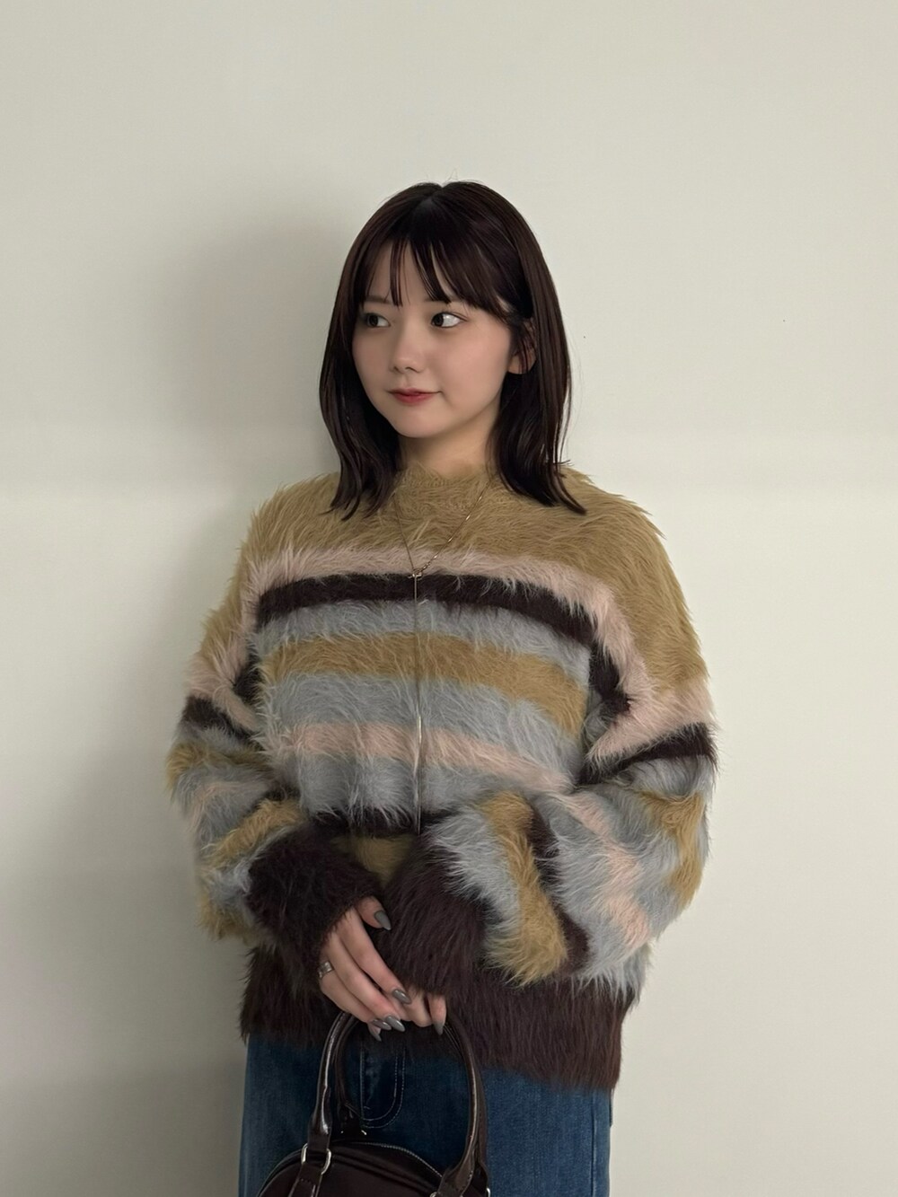 ブルー系のデニムパンツ、イエロー系のニット/セーター、ブラック系のブーツを着用したレディースの冬コーディネートの5枚目の写真