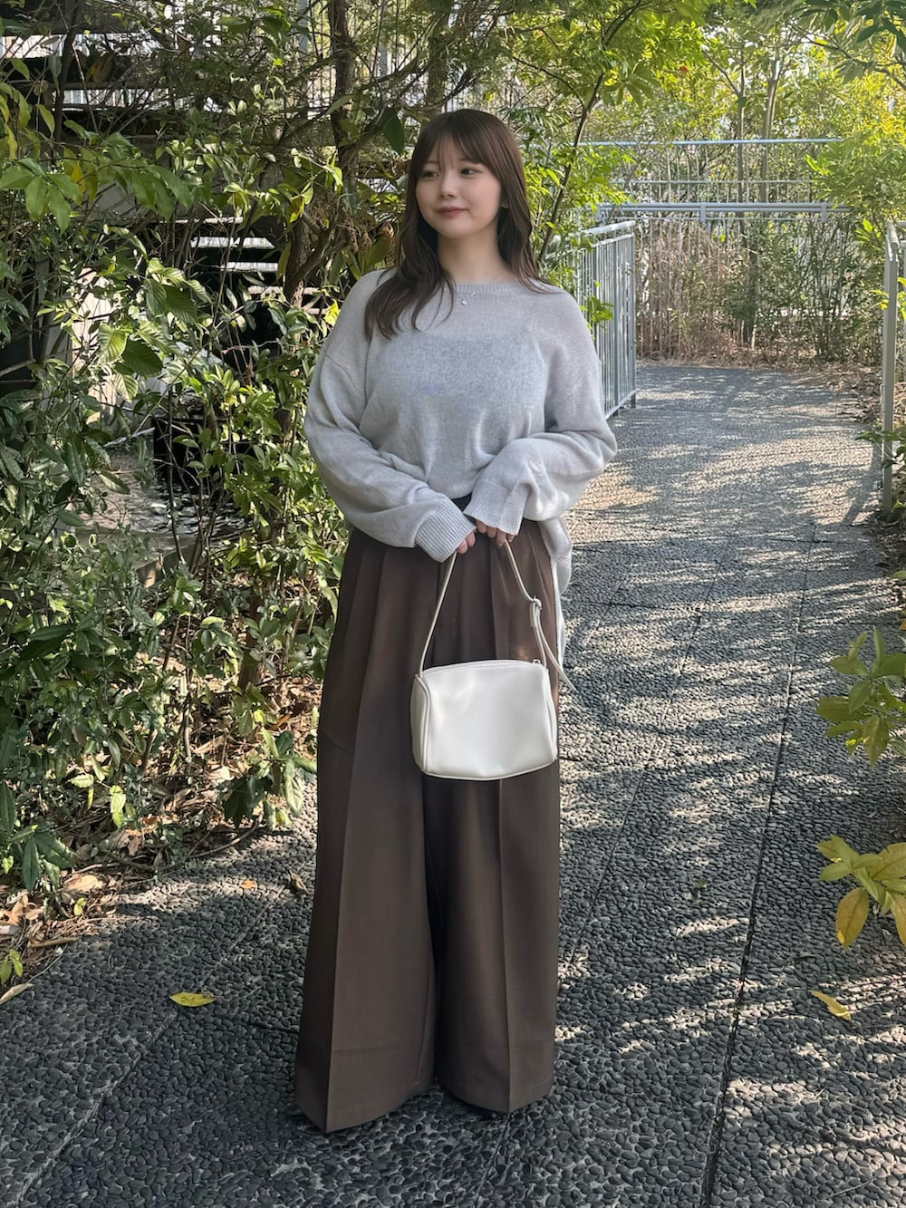 ブラック系のキャミソール、グレー系のニット/セーター、ブラウン系のスラックスを着用したレディースの春コーディネートの2枚目の写真