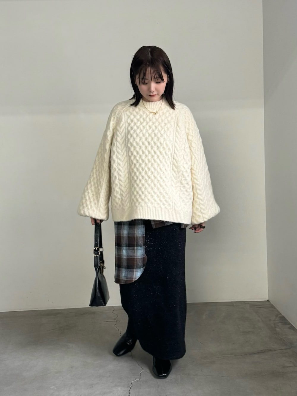 ホワイト系のニット/セーター、ブラウン系のシャツ/ブラウス、ブラック系のスカートを着用したレディースの秋コーディネートの4枚目の写真