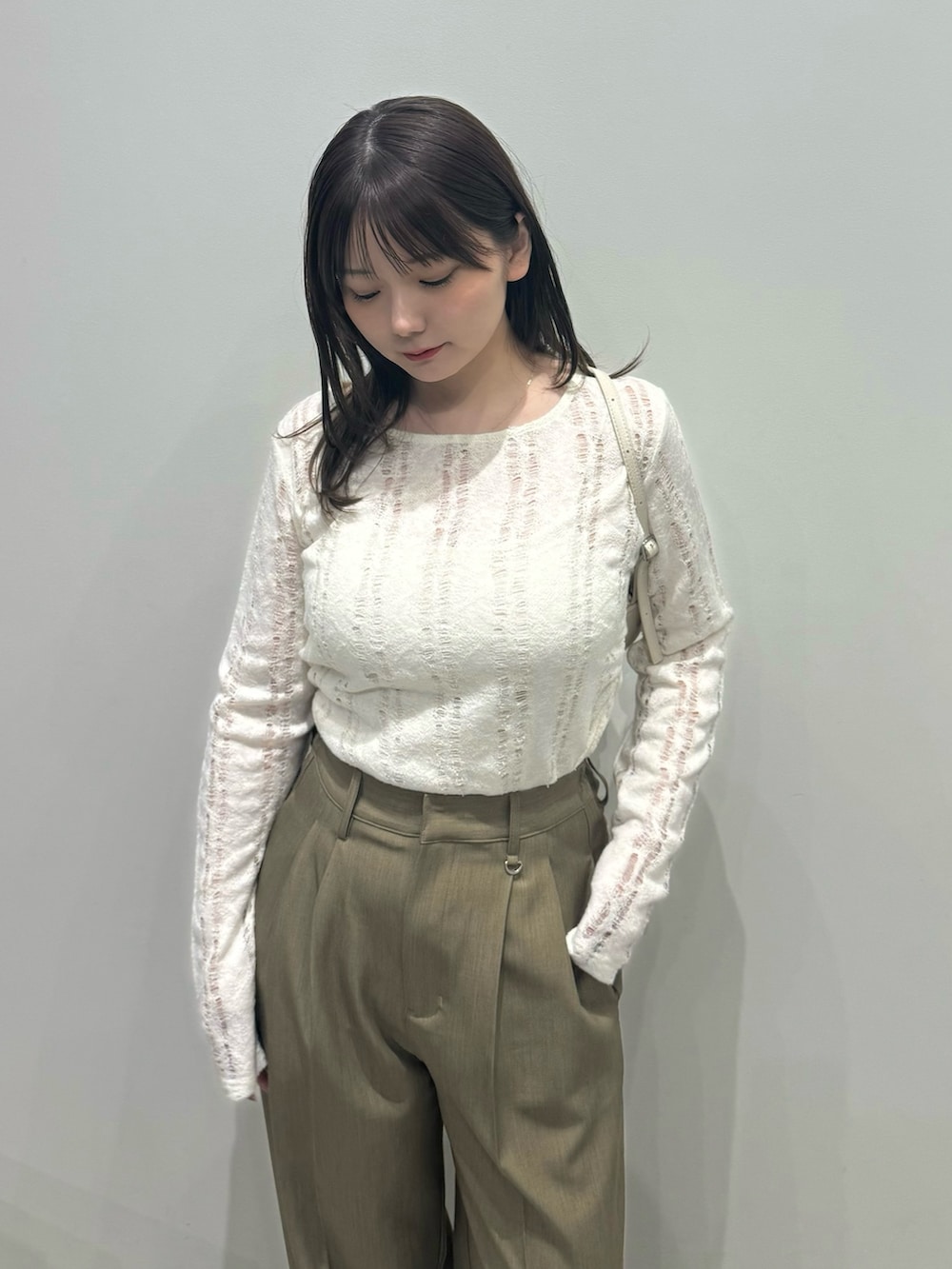 ブラウン系のスラックス、ホワイト系のハンドバッグ、ホワイト系のキャミソールを着用したレディースの春コーディネートの4枚目の写真