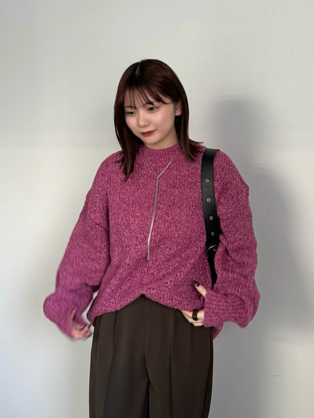 ブラウン系のスラックス、ピンク系のニット/セーター、ブラック系のブーツを着用したレディースの冬コーディネートの3枚目の写真