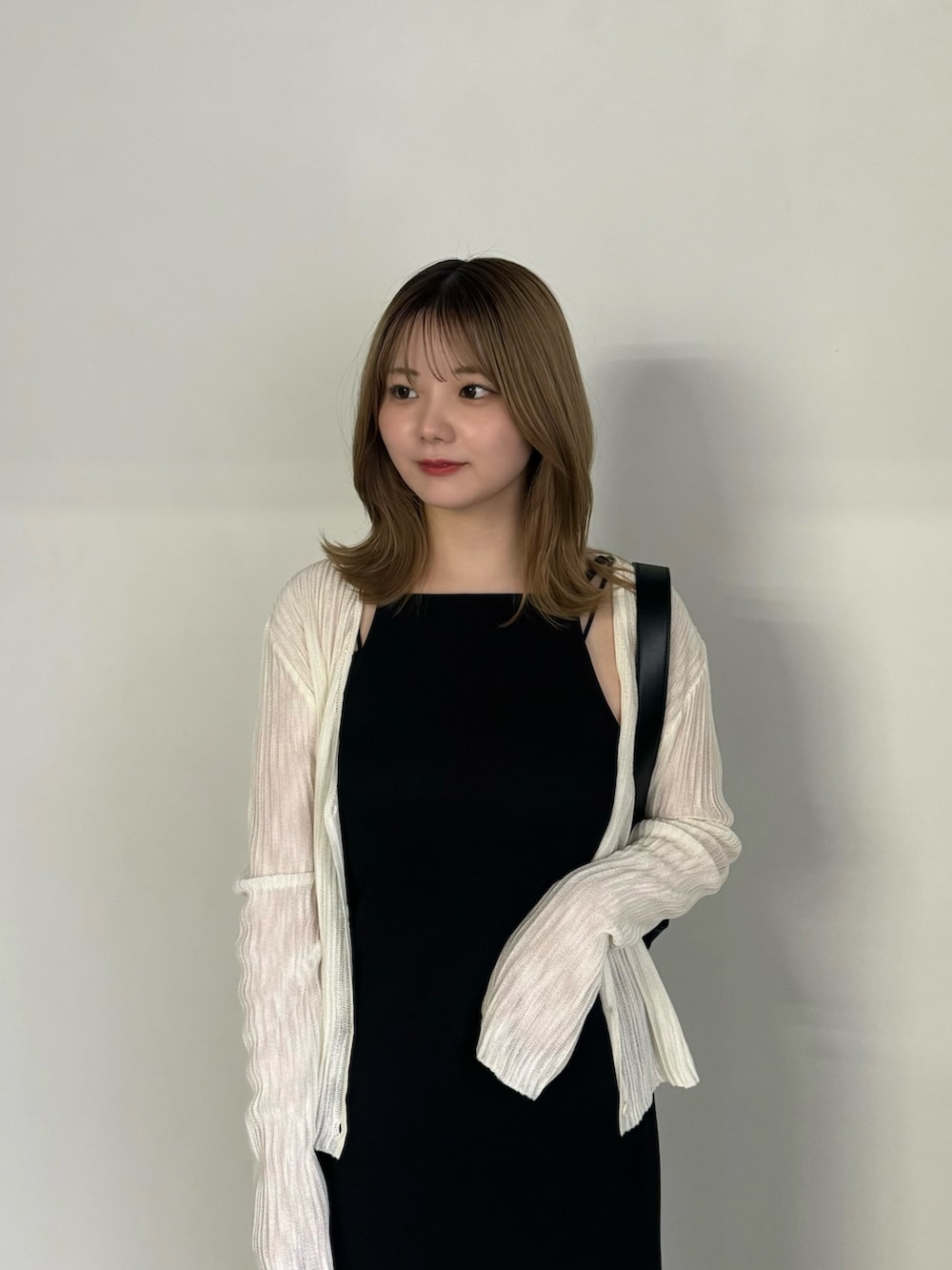 ブラック系のワンピース、ホワイト系のカーディガン/ボレロ、ブラック系のショルダーバッグを着用したレディースの夏コーディネートの5枚目の写真