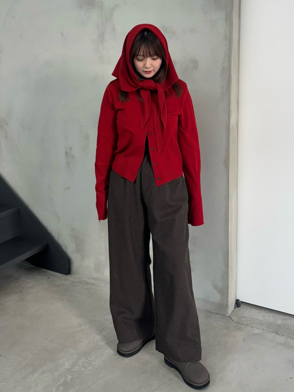 レッド系のニット/セーター、ブラウン系のその他パンツ、グレー系のスリッポンを着用したレディースの冬コーディネートの2枚目の写真