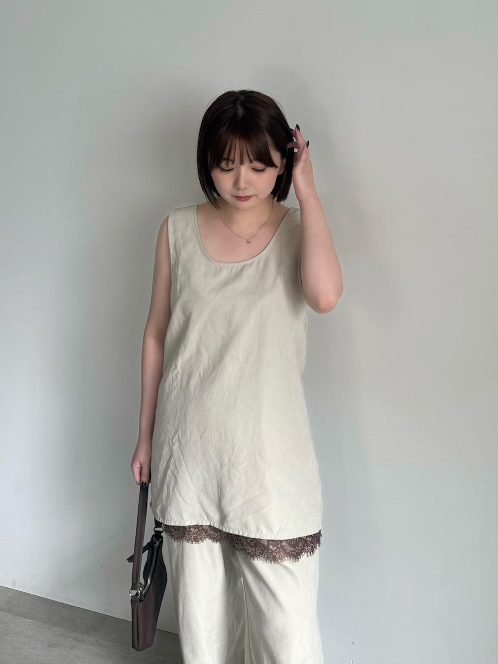 ベージュ系のその他パンツ、ブラウン系のスニーカー、ブラウン系のハンドバッグを着用したレディースの夏コーディネートの2枚目の写真