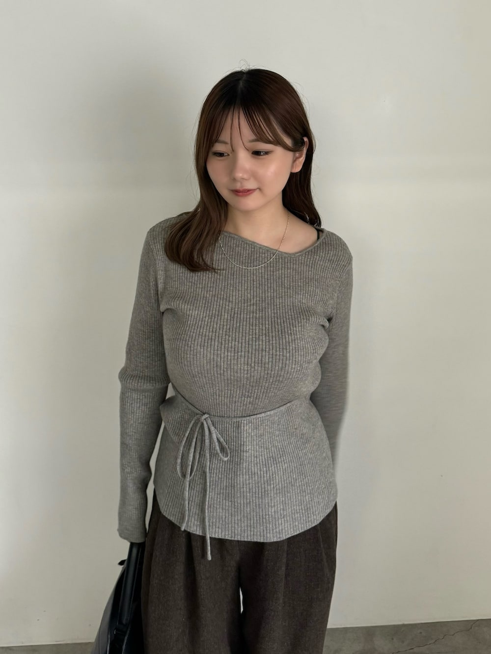 グレー系のニット/セーター、ブラック系のブーツを着用したレディースの秋コーディネートの2枚目の写真