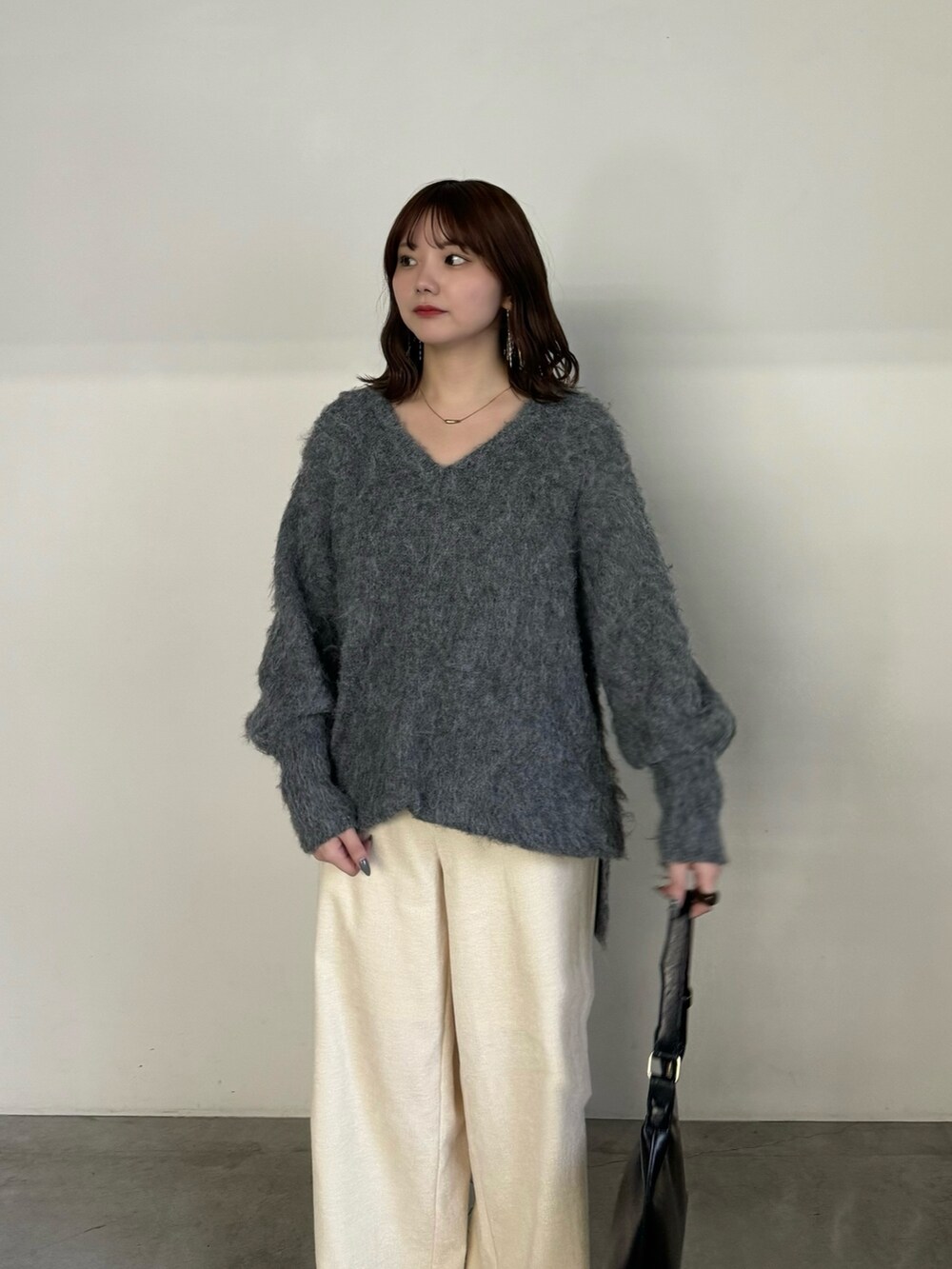 グレー系のニット/セーター、ホワイト系のその他パンツ、ブラック系のハンドバッグを着用したレディースの冬コーディネートの4枚目の写真
