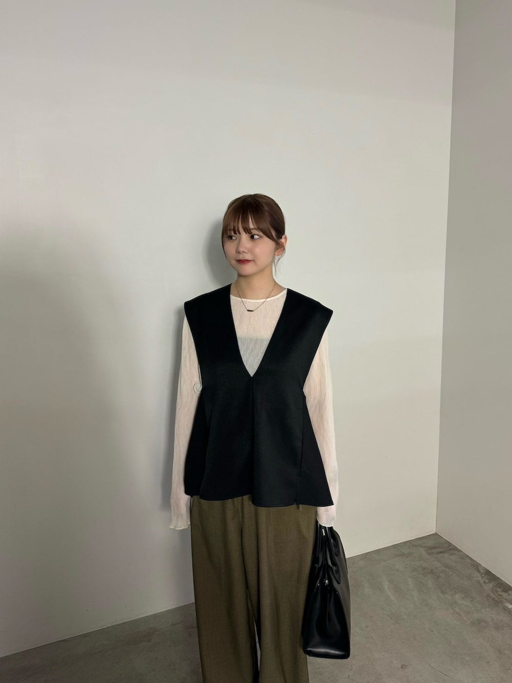 ブラック系のベスト、ブラウン系のスラックス、ホワイト系のTシャツ/カットソーを着用したレディースの冬コーディネートの4枚目の写真