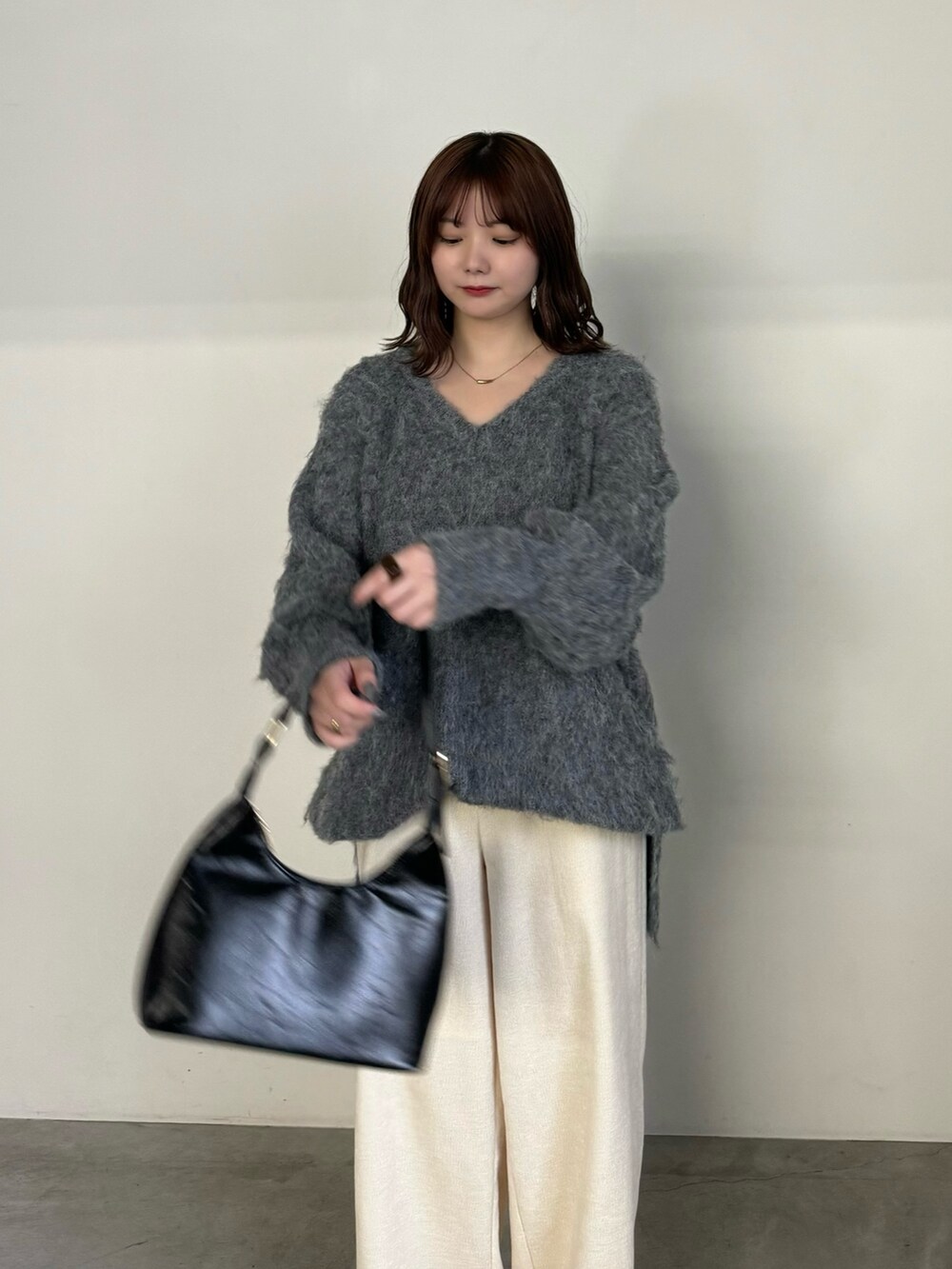 グレー系のニット/セーター、ホワイト系のその他パンツ、ブラック系のハンドバッグを着用したレディースの冬コーディネートの5枚目の写真
