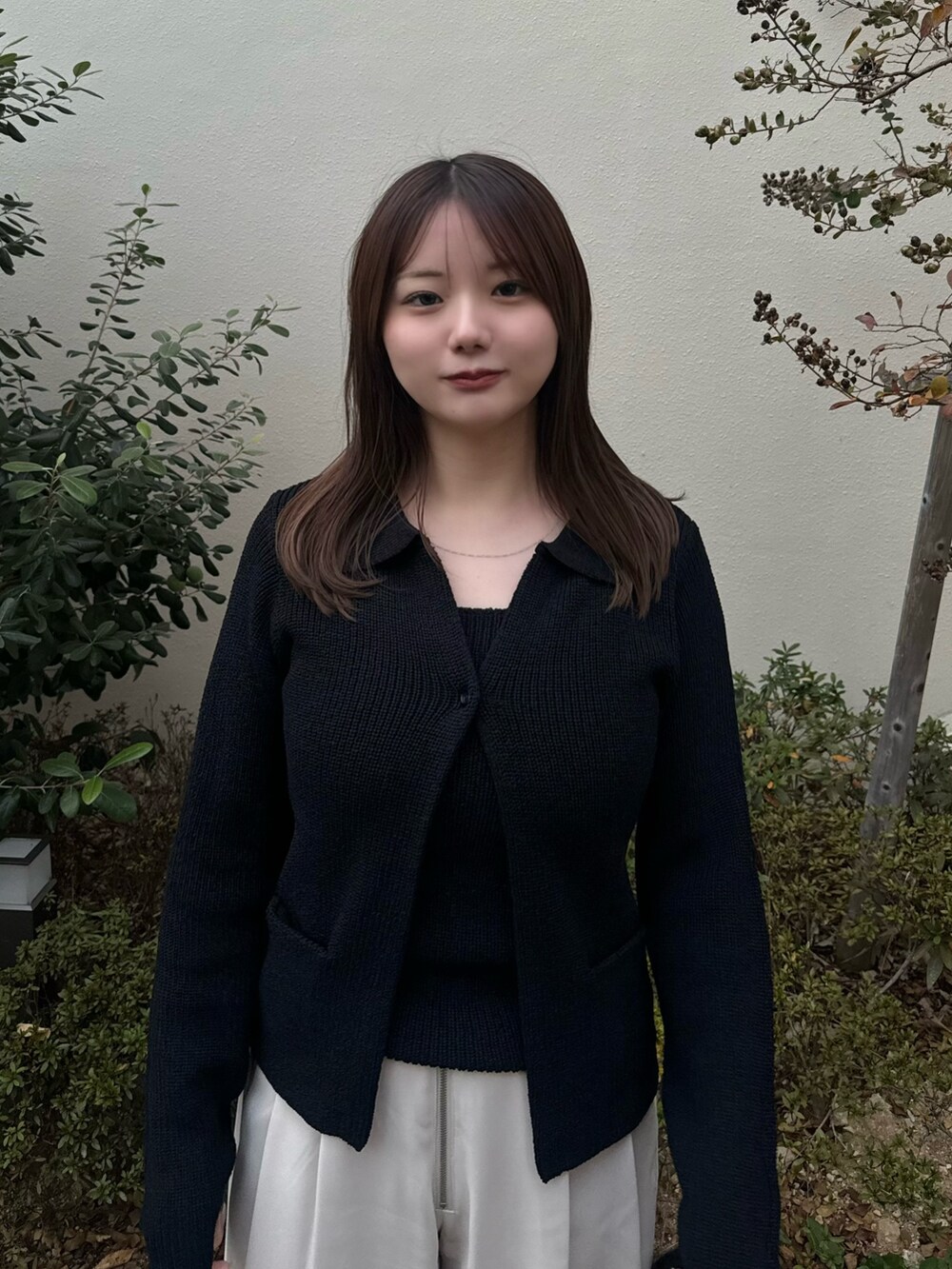 ブラック系のカーディガン/ボレロ、ホワイト系のスラックスを着用したレディースの秋コーディネートの4枚目の写真