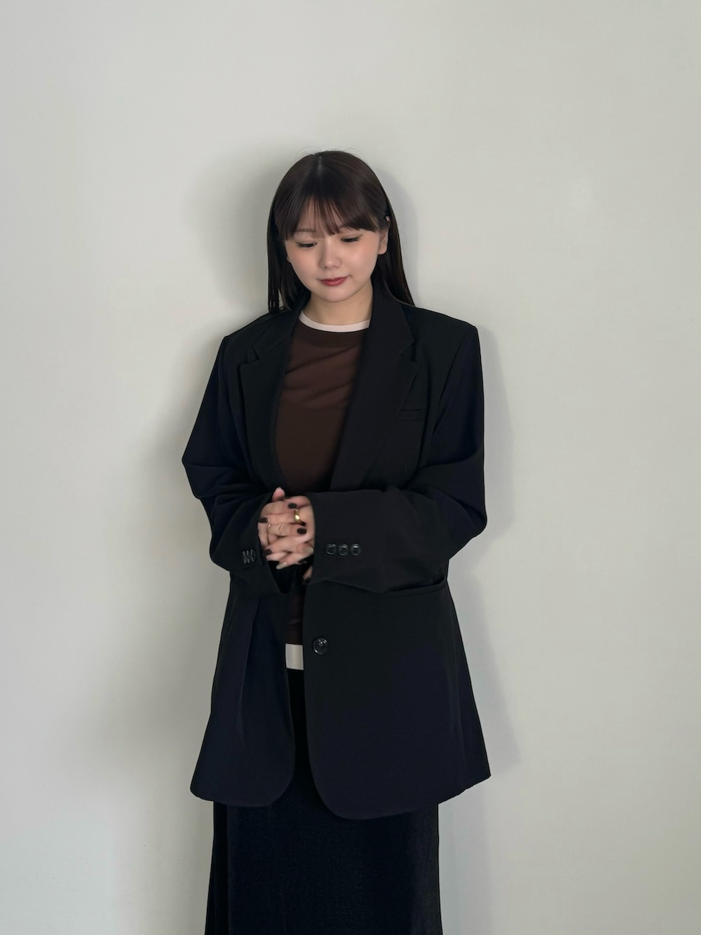 ブラウン系のTシャツ/カットソー、ブラック系のテーラードジャケット、ブラック系のスカートを着用したレディースの冬コーディネートの4枚目の写真