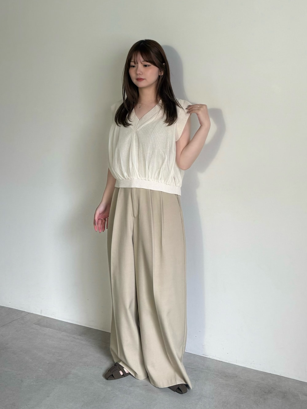 ベージュ系のベスト、ブラック系のキャミソール、ベージュ系のスラックスを着用したレディースの夏コーディネートの4枚目の写真