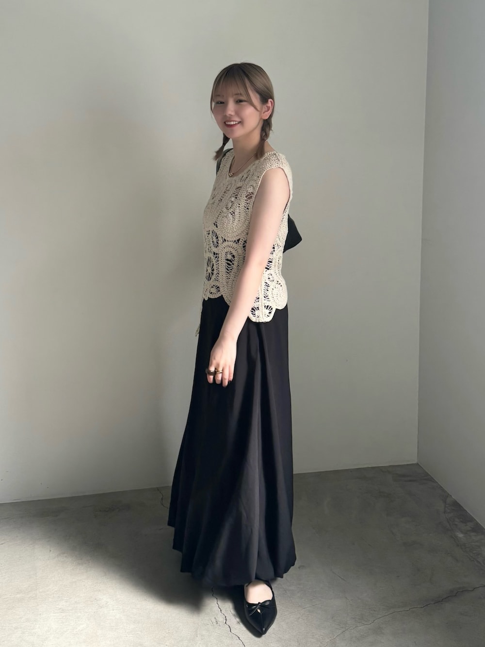 ブラック系のスカート、ブラック系のパンプス、ブラック系のハンドバッグを着用したレディースの春コーディネートの2枚目の写真