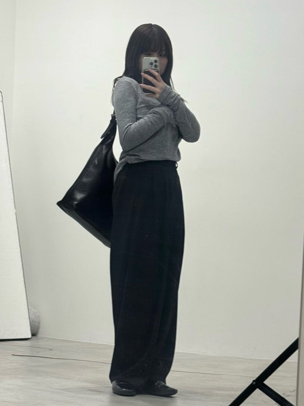 ブラック系のスラックス、グレー系のTシャツ/カットソー、ブラック系のショルダーバッグを着用したレディースの冬コーディネートの2枚目の写真